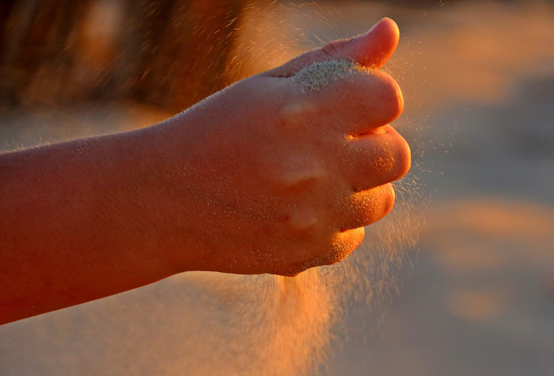 Sand rieselt durch Hand